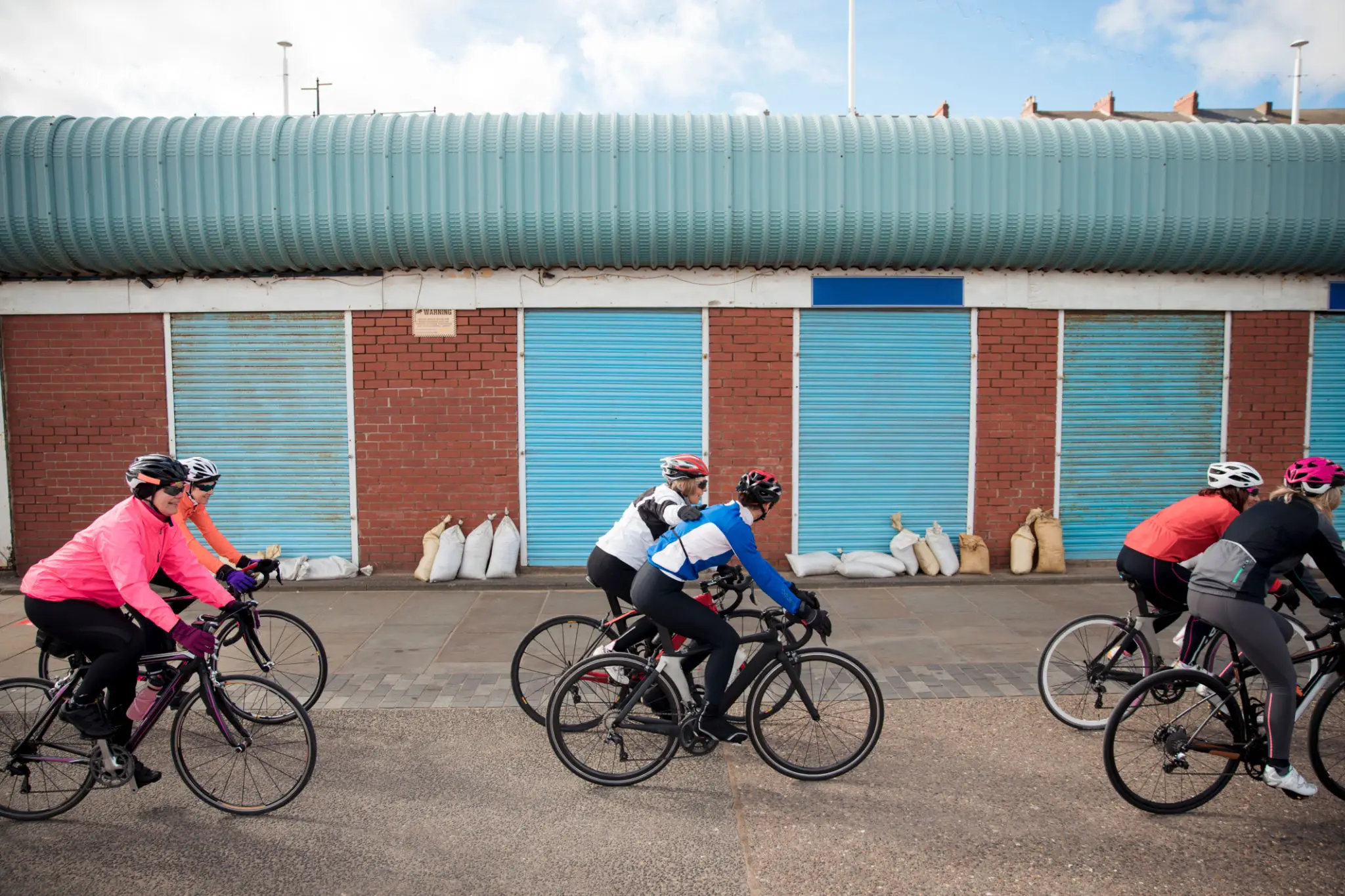 Bikers in colorful gear passing warehouses