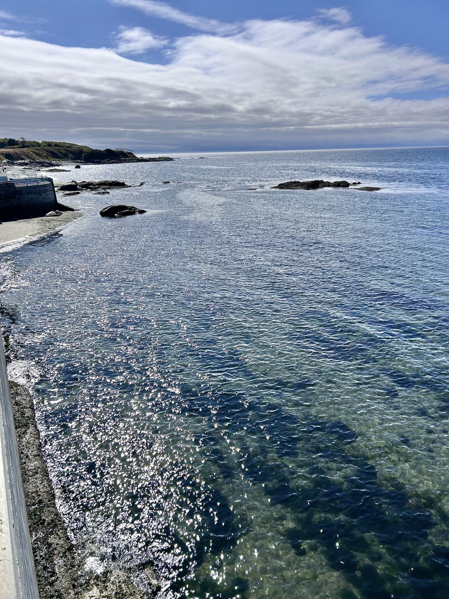 Sunlit clear coastal waters with rocky shoreline