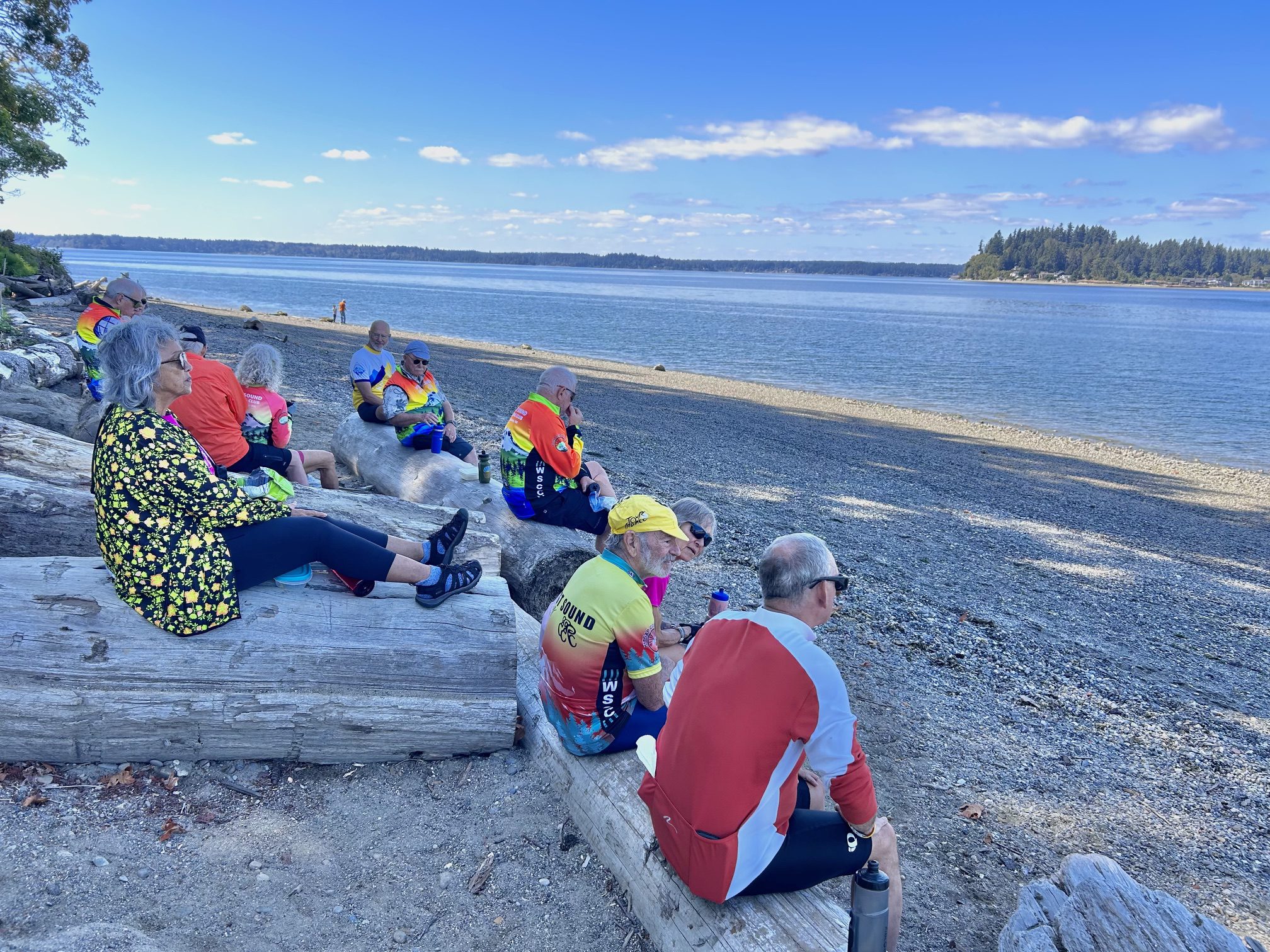 Cyclists resting on driftwood by the beach